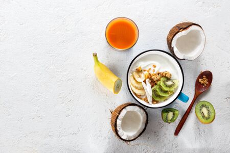 Coconut yogurt fruits with granola served on light background. Probiotic food concept. Tasty and healthy breakfastの写真素材
