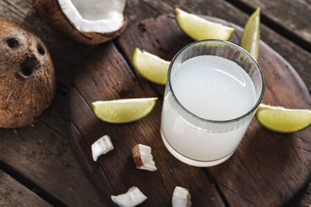 Coconut with coconut water in glass cup on wooden table. Healthy drinks conceptの写真素材