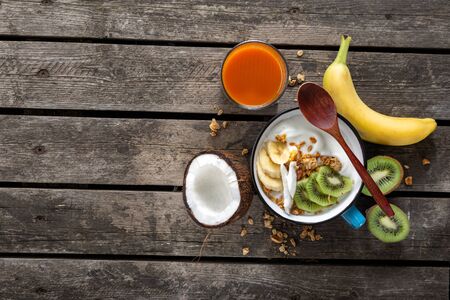 Delicious coconut yogurt with granola and fruit served on rustic wooden table with copy space. Healthy vegan food concept. Tasty and healthy breakfastの写真素材