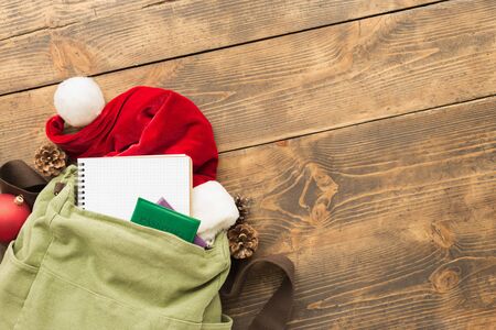 Planning for travel concept. Vintage backpack with blank notebook, santa claus hat, passports and...