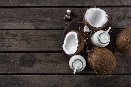 Coconut milk in bottles on wooden table. Vegan non dairy healthy drink. Healthy eating conceptの写真素材