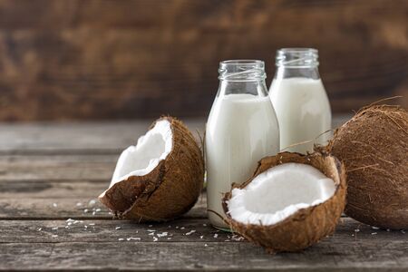 Coconut milk in bottles on wooden table. Vegan non dairy healthy drink. Healthy eating conceptの写真素材