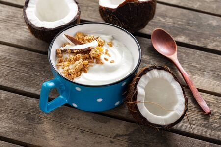 Probiotic food concept. Bowl of homemade coconut yogurt with granola on wooden table. Healthy vegan food. Tasty and healthy breakfastの写真素材