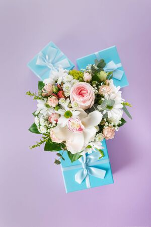 Composition of bouquet of flowers and gift boxes on a colorful background flat lay top viewの写真素材