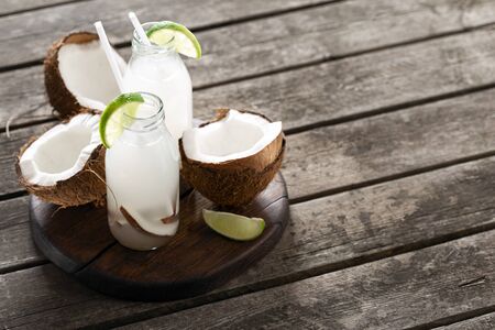 Fresh coconut water in bottles on wooden tableの写真素材