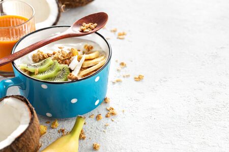 Organic coconut yogurt with granola and fruits kiwi and bananas in cup on light background with copy spaceの写真素材