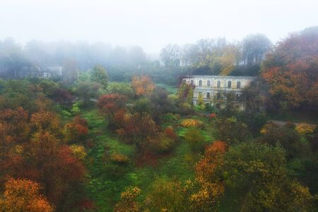 Beautiful autumn landscape with an abandoned mysterious house in the fogの写真素材