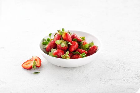 Heap of fresh strawberries in ceramic bowl on white backgroundの写真素材