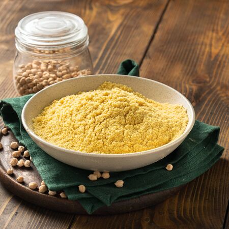 Chickpea flour in white ceramic bowl on wooden table with copy spaceの写真素材