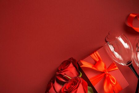 Valentine's day or mother's day concept. Red gift box with flowers rose and wine glasses on red background Copy Space Top viewの写真素材