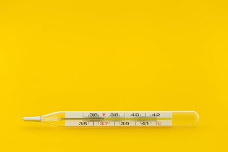 Close up thermometer with temperature of 37 on yellow backgroundの写真素材