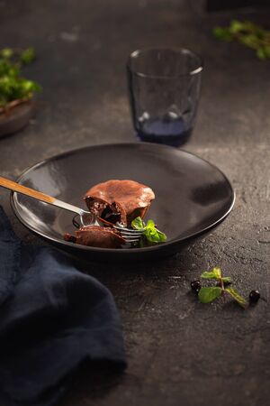 Chocolate muffin with chocolate filling in black plate on dark backgroundの写真素材
