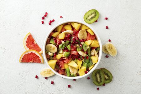 Fresh fruit salad on light surface top view Summer food concept