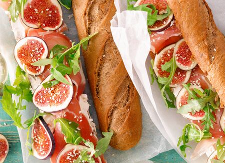 Sandwich with prosciutto, mascarpone cheese and figs on green background top viewの写真素材