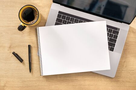 Online work concept Blank notebook with laptop and cup coffee on wooden table top viewの写真素材