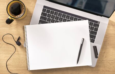 Online education concept Blank notebook with laptop, cup coffee and microphone on wooden table top viewの写真素材