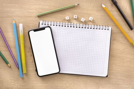 Office desk with notebook, smartphone, word idea and colored markers and pencils top viewの写真素材