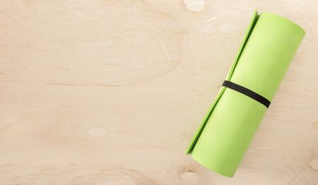 Green yoga mat or sport activity on wooden background top view