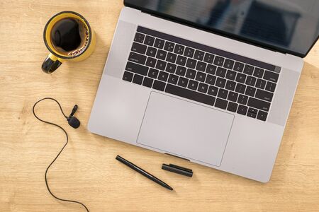 Online education concept Blank notebook with laptop, cup coffee and microphone on wooden table top viewの写真素材