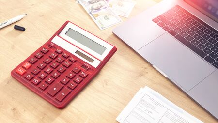 Payment of taxes or bills concept. Office desk with calculator, laptop, utility bills and moneyの写真素材