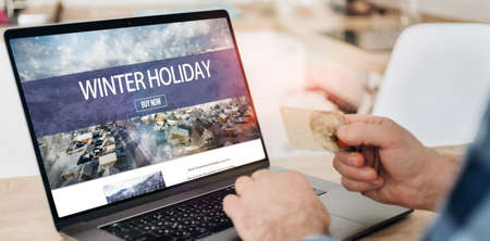 Man holding credit card and chooses winter holidays Internet