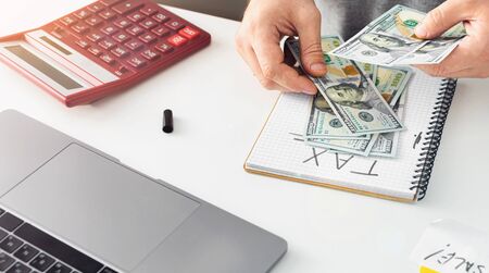 Tax day concept. Business man counts money for taxesの写真素材