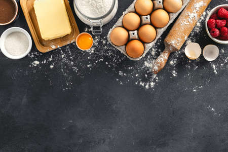 Ingredients for cooking raspberry and chocolate pie on dark background with copy space Bakery...