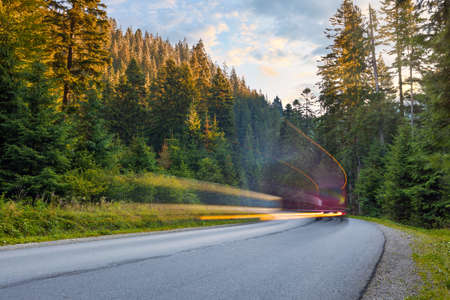 Travel concept. Blurred bus in motion is driving on mountain road in the autumn forestの写真素材
