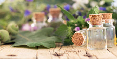 Glass bottle with essential oil or oil for natural diseases treatment on wooden table with copy space. Natural herbal medicine conceptの写真素材