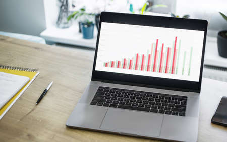 Open laptop with business charts on the table in the home office. Remote Worker Conceptの写真素材