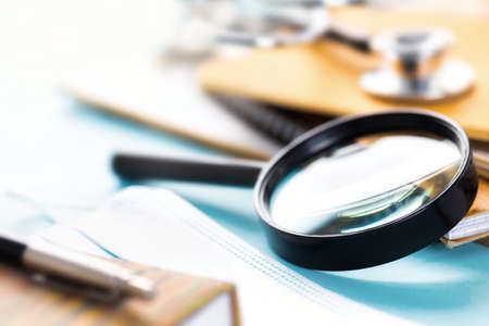 Doctor's workplace with magnifying glass, stethoscope or phonendoscope, notebooks and documentsの写真素材