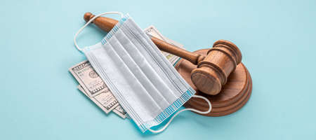 Judge gavel with medical mask and money on blue background. Corruption in the medical field conceptの写真素材