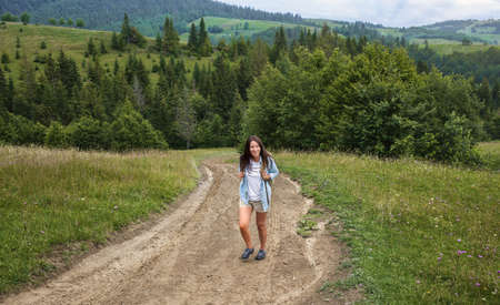 Happy young woman tourist walks with backpack in the highlands. Active and healthy lifestyle conceptの写真素材