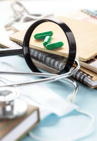 Doctor desk magnifying glass, capsules, stethoscope or phonendoscope, notebooks and documentsの写真素材
