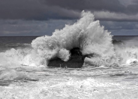 A big wave hitting a rock at shore, splashing, seen at a beach on Tenerife, Spain.の写真素材