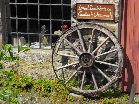 An old Scottish farm with a shed and an old, wooden wheel in front of itの写真素材