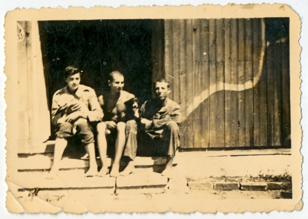CIRCA 1945  Three men sitting on the porch of the house with the puppy in his arms