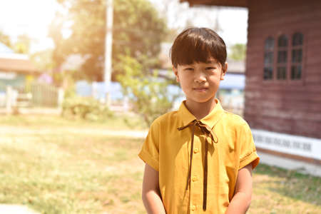 A little girl in yellow shirt stands in front of a home. Blurred back backgroundのeditorial素材