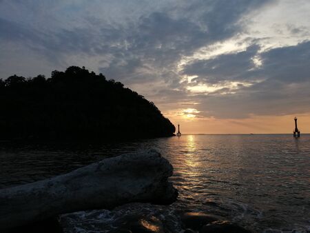 Watching the sun set at the horizon from the beachの写真素材