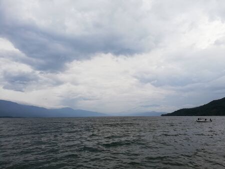 Dramatic view of the clouds on a wavy lakeの写真素材