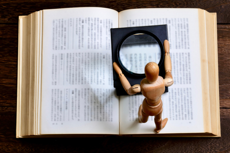 A wooden figurine on an open book, reading conceptの写真素材