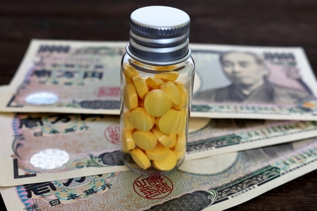 Medical capsule and yen currency on wooden tableの写真素材