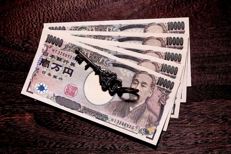 key and 10000 yen money on wooden tableの写真素材