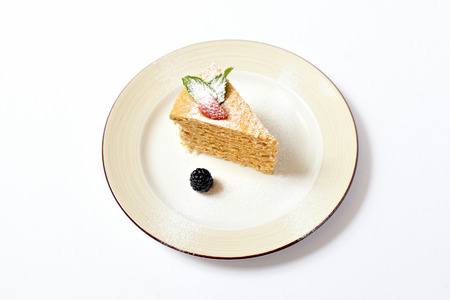 Piece of multilayer cake with powdered sugar and berries isolated on white