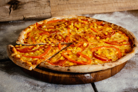 Pizza with tomatoes and corn isolated on wood backgroundの写真素材