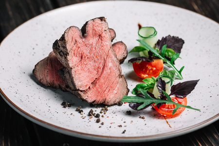 Grilled beef steak with salad on dark wooden backgroundの写真素材