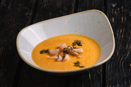 Pumpkin cream soup with shrimp on dark wood backgroundの写真素材
