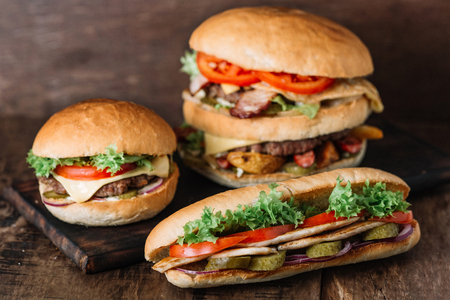 Chicken sandwich and two different kinds of hamburgers on wooden tableの写真素材