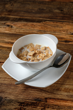 Bowl of cornflakes with milk on brown wooden backgroundの写真素材