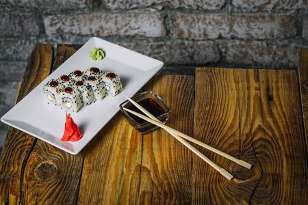 Plate of sushi on wooden table in front of stone wallの写真素材